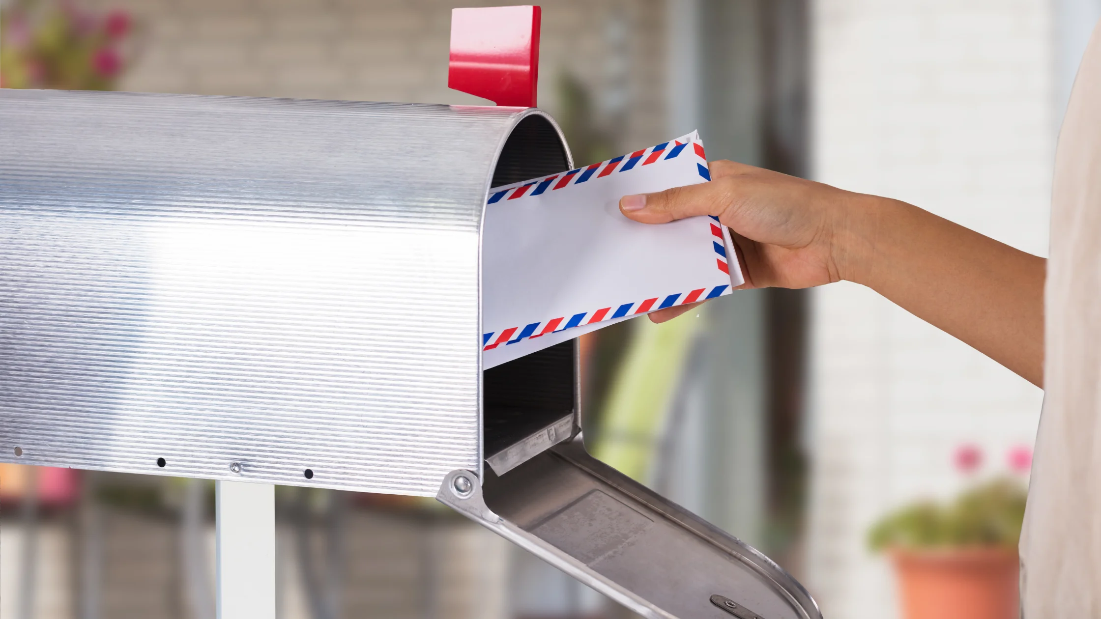 Eine Hand zieht einen Brief aus einem Briefkasten, als Sinnbild für Schreiben der Agentur für Arbeit zur Sperrzeit beim Arbeitslosengeld.