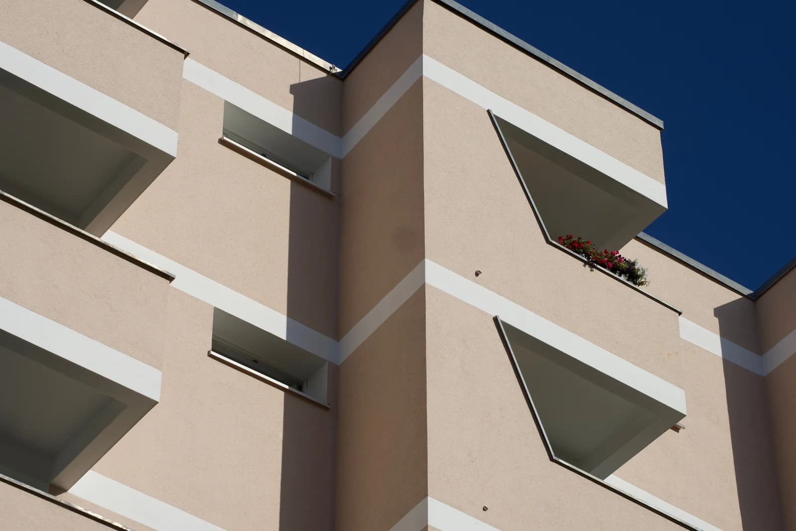 Die Fassade eines Wohnhauses mit Balkonen vor blauem Himmel.