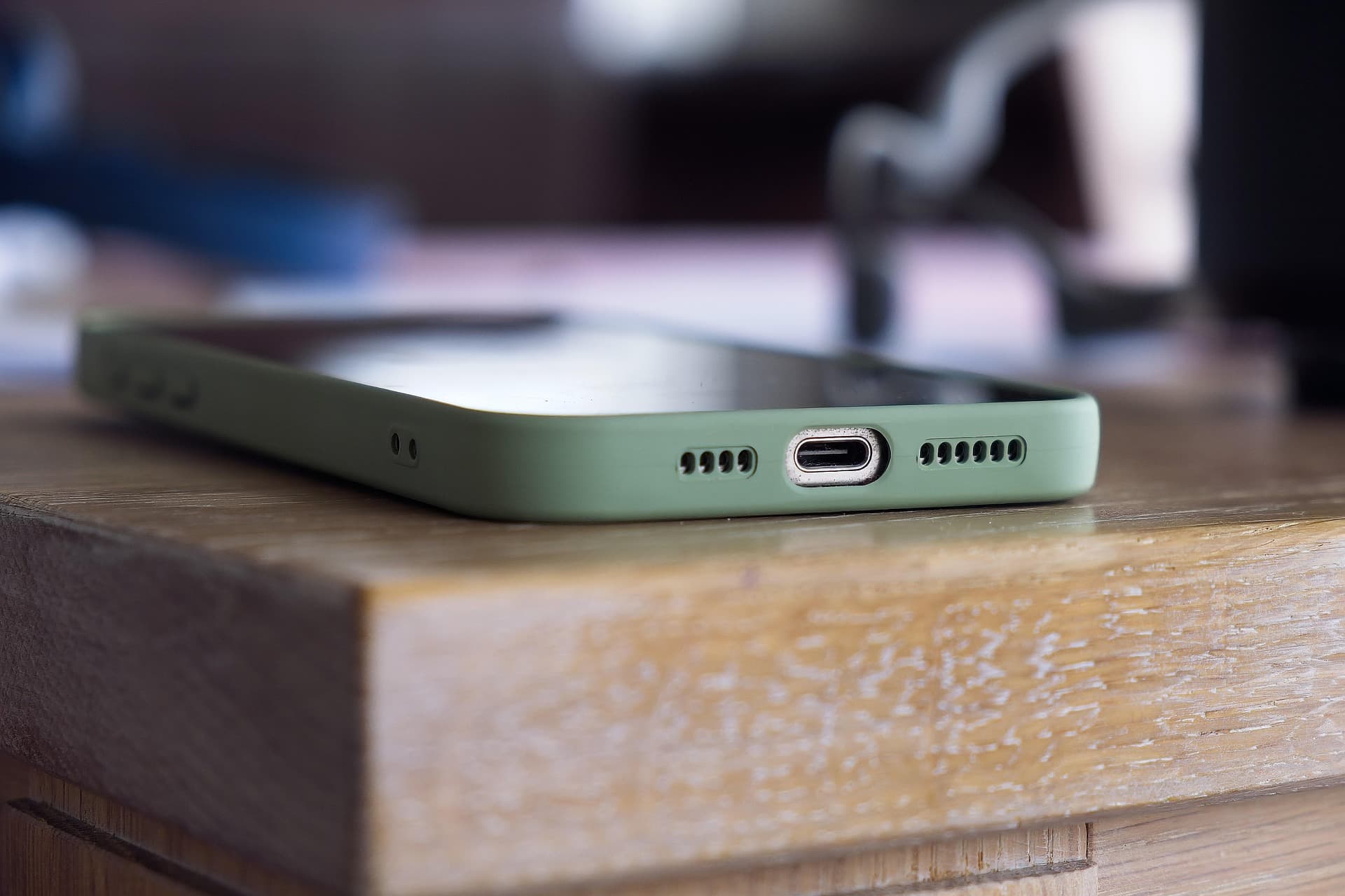 Nahaufnahme eines Smartphones mit grüner Hülle auf einem Holztisch