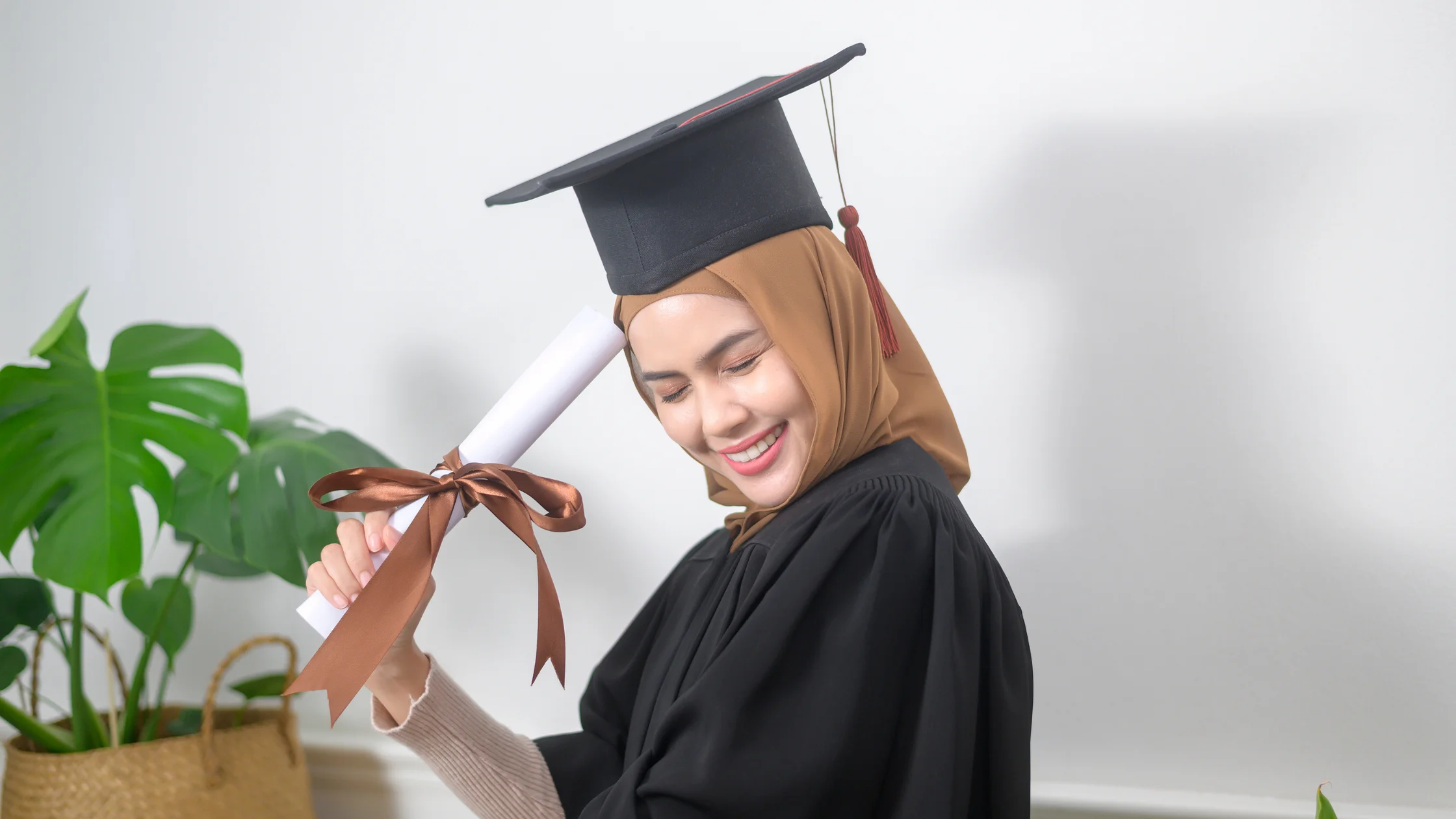 Lachende Frau mit Doktorhut und Talar hält eine zusammengerollte Urkunde in der Hand, als Symbol für den Abschluss nach der Weiterbildung